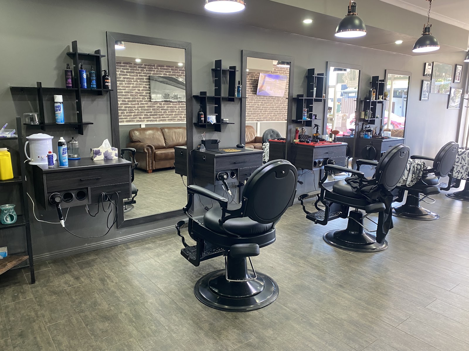 Inside Cut & Shave Barber: black barber chairs, mirrors and a brick feature wall